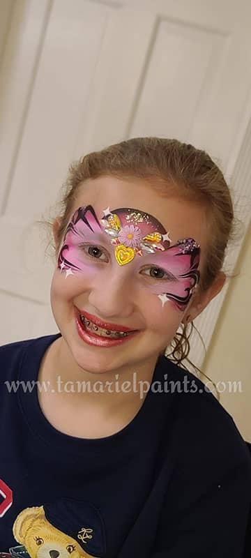 A girl with colorful butterfly and flower airbrush face paint