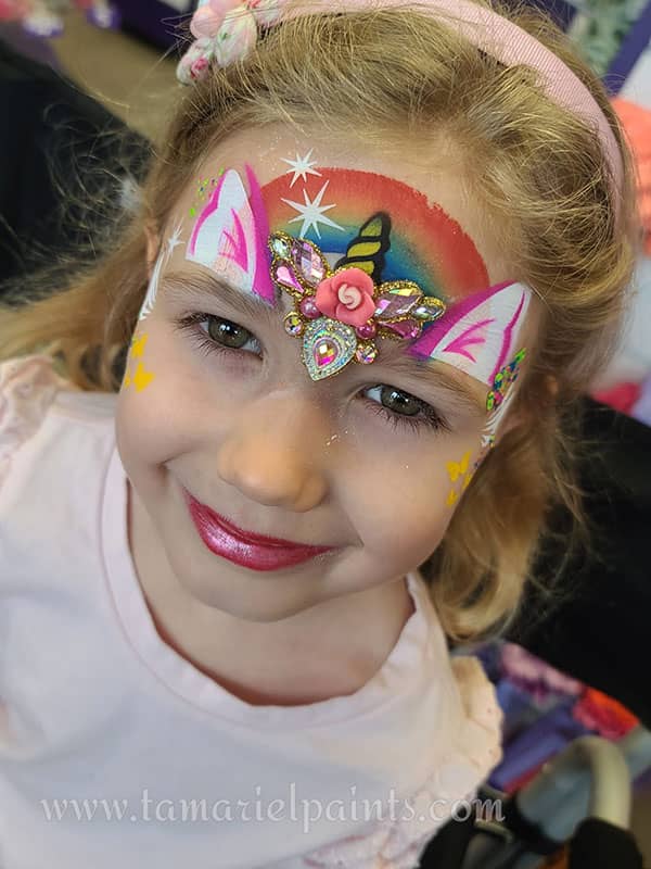 A girl with colorful unicorn airbrush face paint