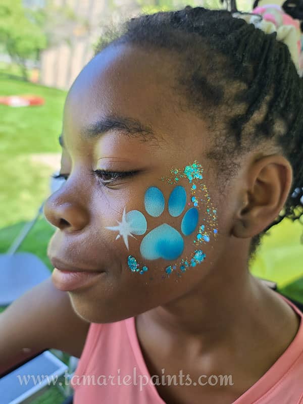 A girl with colorful paw print airbrush face paint