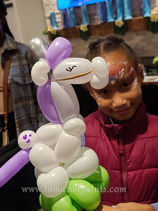 A child holds a twisted balloon unicorn