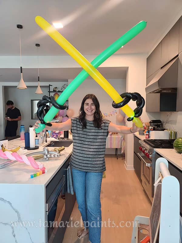 A woman holds two colorful twisted balloon swords