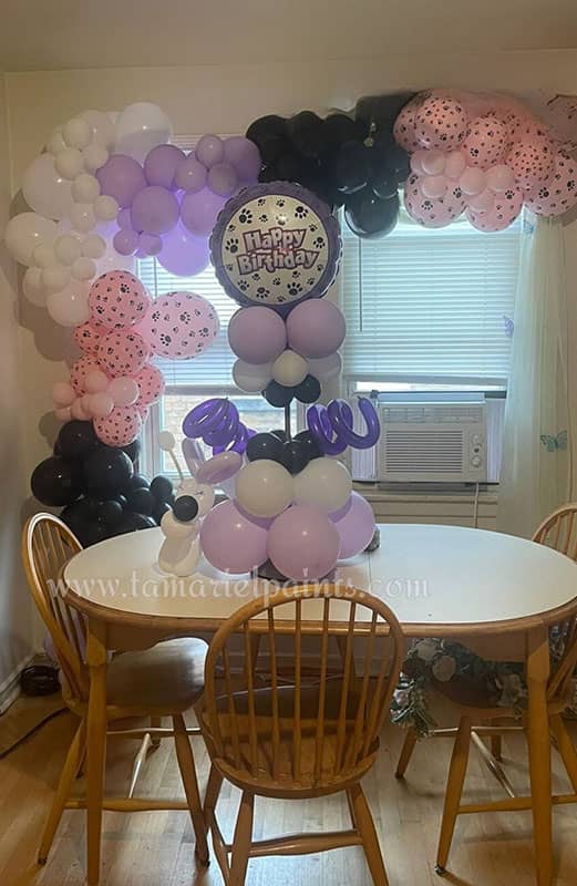 An arch of white purple and pink birthday balloons with table display