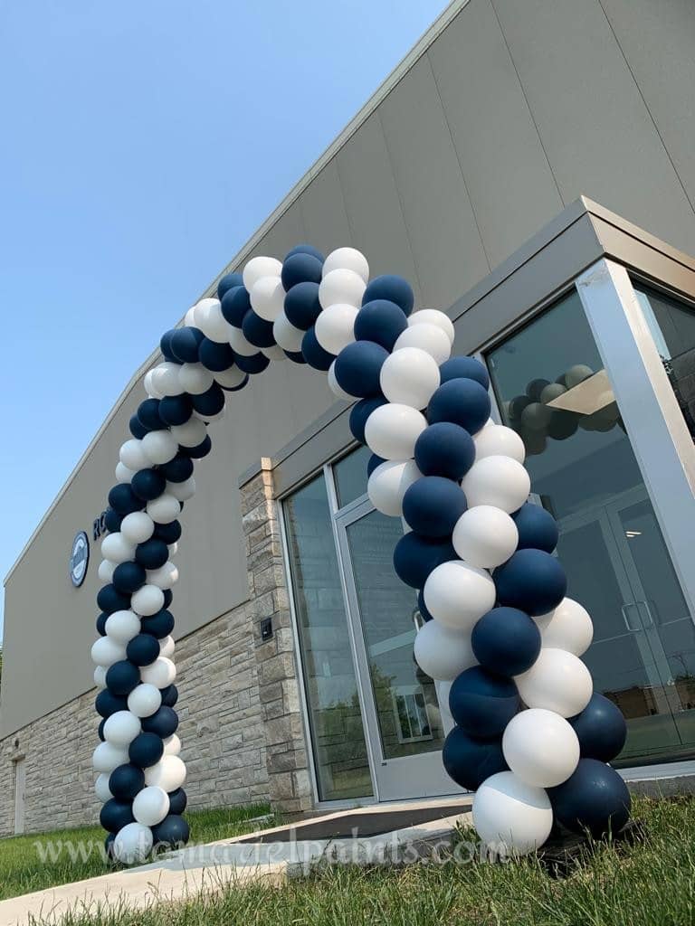 An arch of white and black balloons at a building entrance