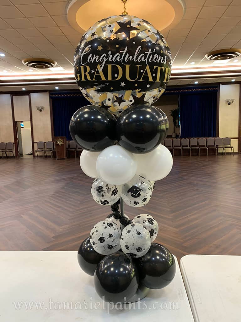 A creative display of white and black balloons in a single column with a Congratulations Graduate balloon at the top