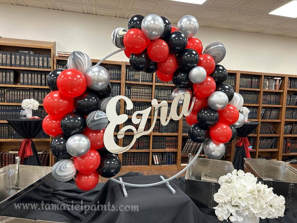 A display of red, silver and black balloons with the word Ezra in the middle