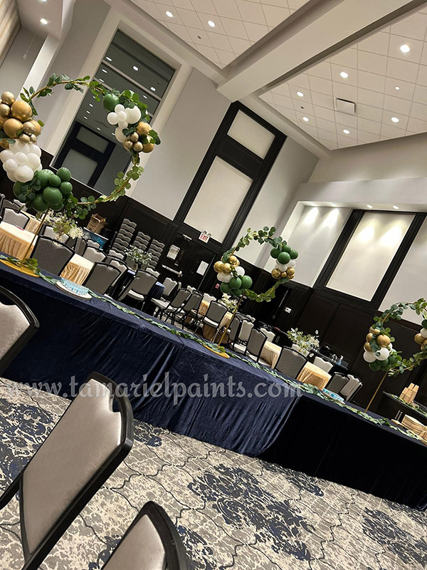 A photo of artistic, circular balloon displays with green, white and gold balloons on a table at an event