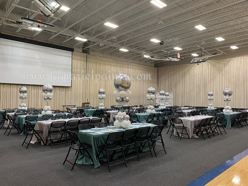 A photo showing tables set up in an event space and creative balloon displays made with white and silver balloons on each table