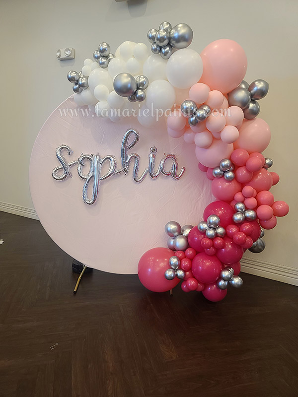 A photo of a balloon display with pink, white and silver baloons