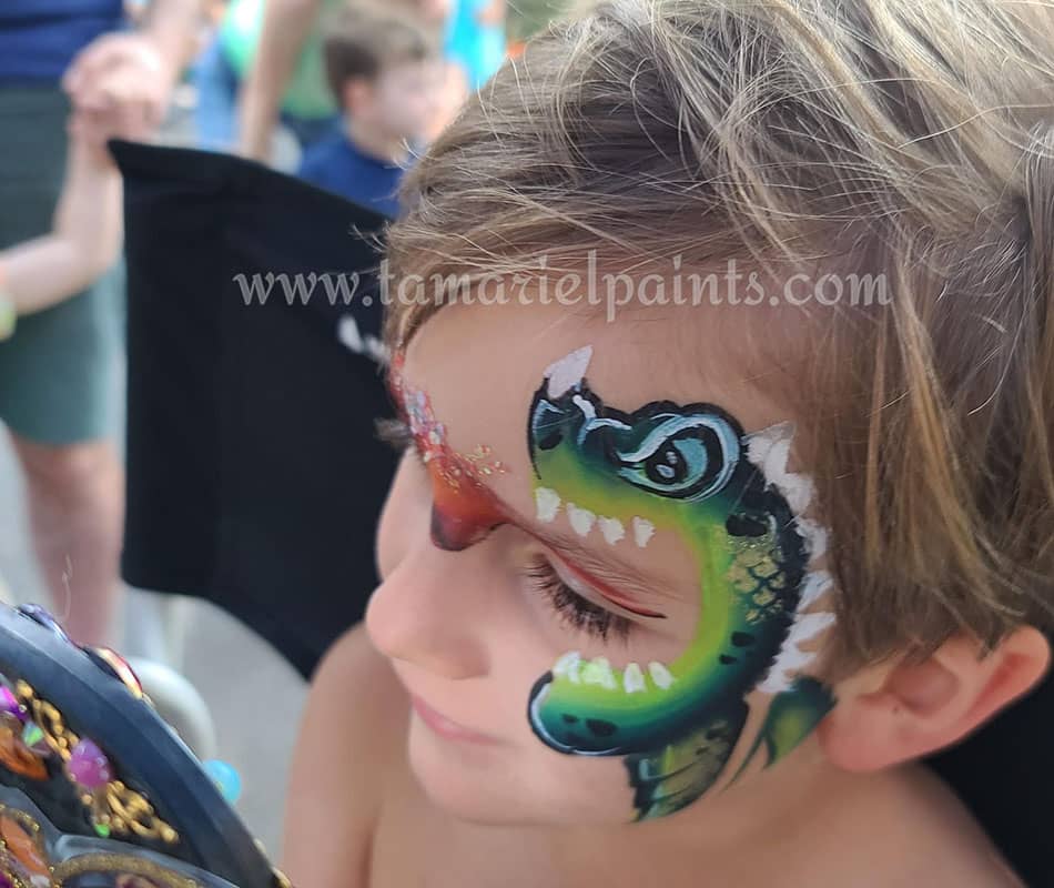 A boy with colorful dragon themed face paint