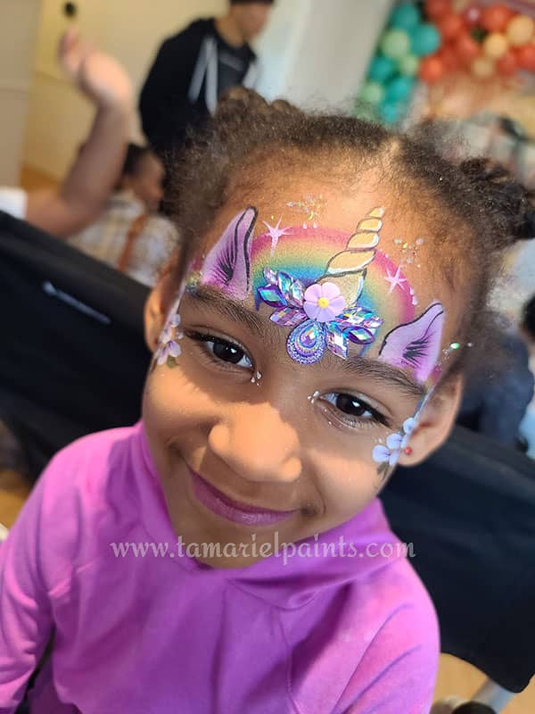 A girl with colorful unicorn themed face paint