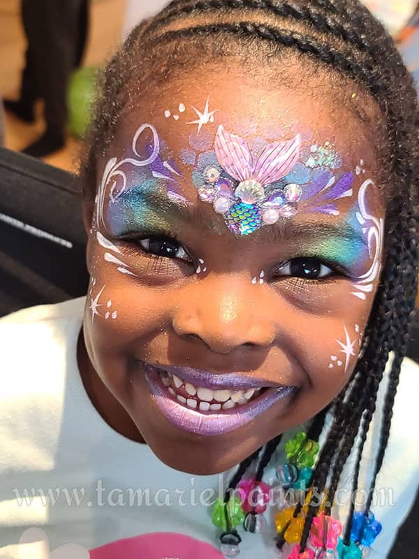 A girl with colorful mermaid themed face paint