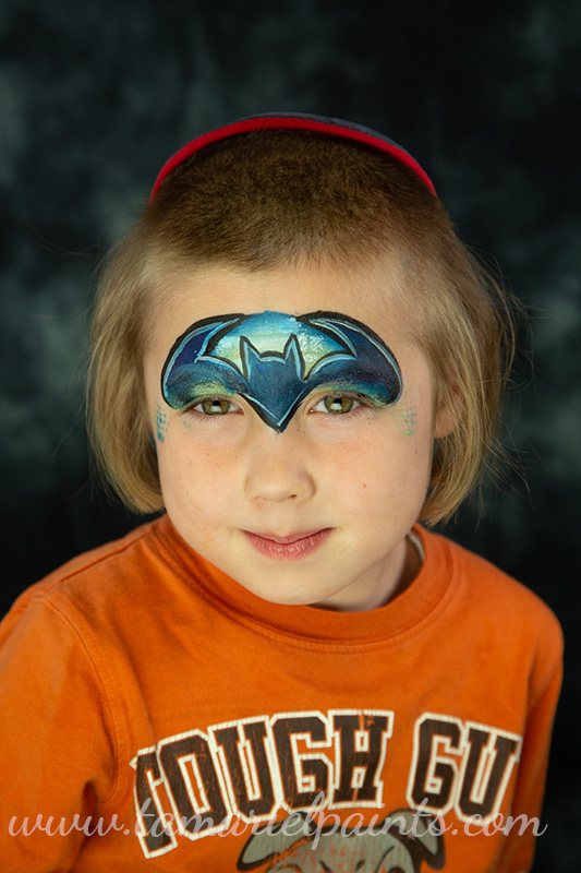 A photo of a child with a Batman symbol face paint