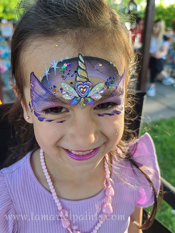 A girl with colorful unicorn themed face paint