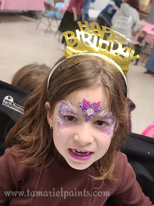 A girl with colorful face paint at a birthday party