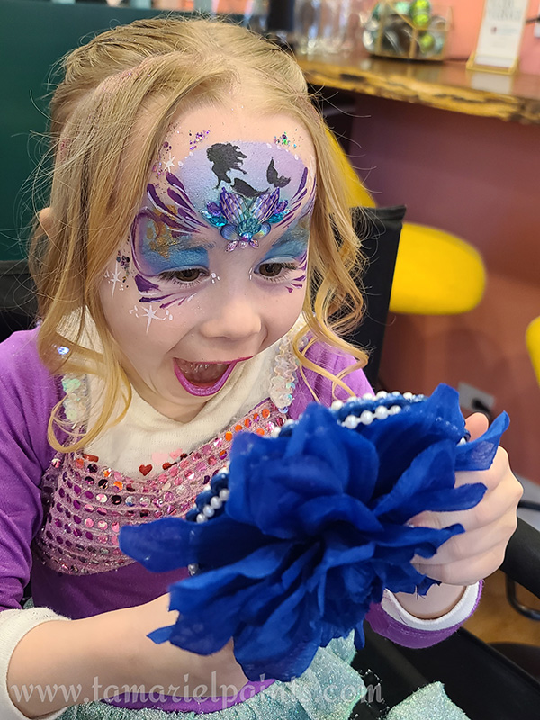 A girl with colorful mermaid themed face paint