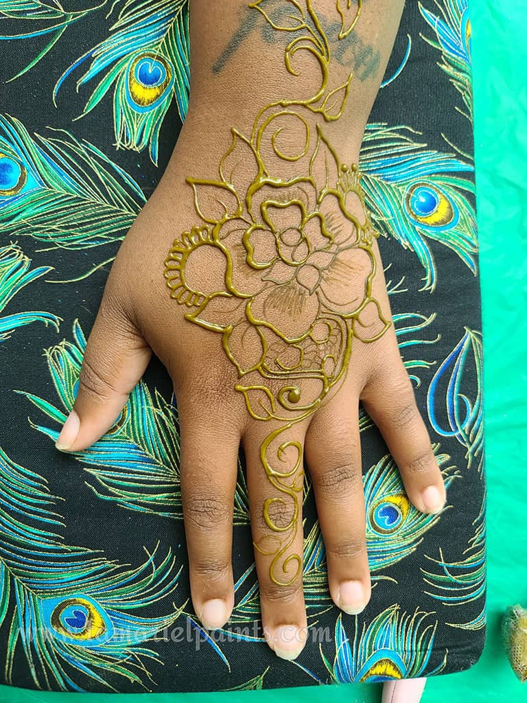 A hand with an intricate floral henna tattoo pattern