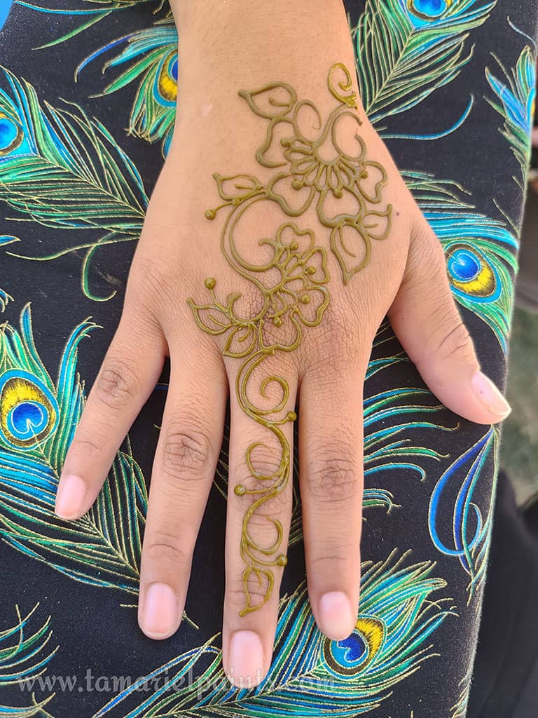 A hand with an intricate floral henna tattoo pattern