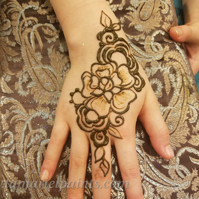 A hand with a intricate floral henna tattoo pattern