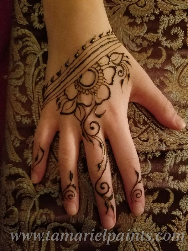 A hand with an intricate floral henna tattoo pattern