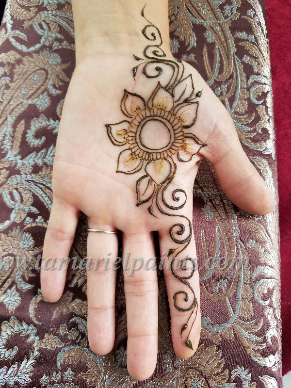 A hand with an intricate floral henna tattoo pattern