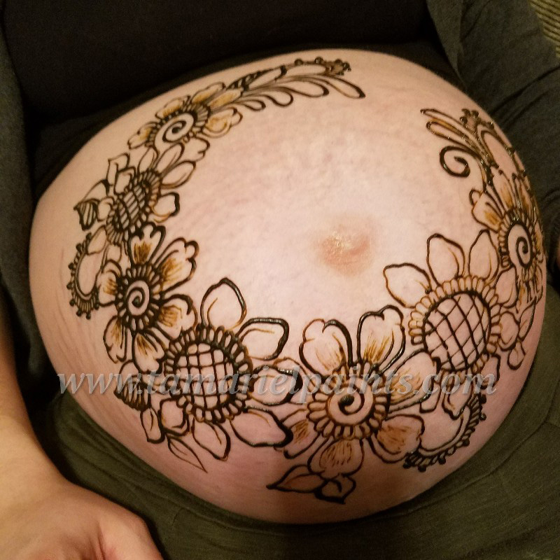 An intricate floral henna stomach tattoo