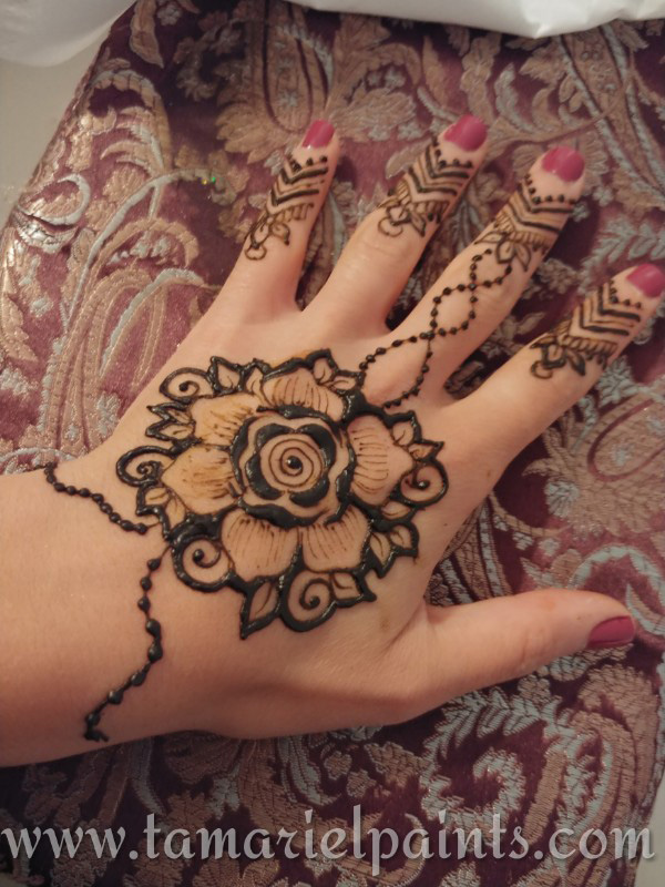 A hand with a intricate floral henna tattoo pattern